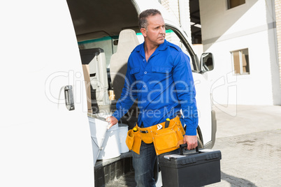 Serious handsome handyman holding toolbox