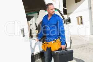 Serious handsome handyman holding toolbox