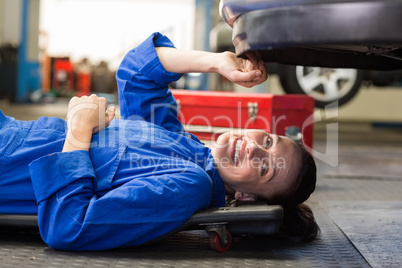 Mechanic lying and working under car