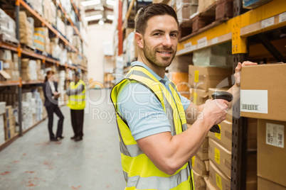 Warehouse worker scanning box while smiling at camera