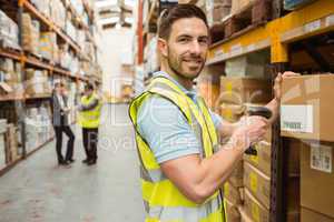 Warehouse worker scanning box while smiling at camera