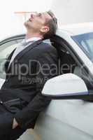 Upset businessman leaning on his car