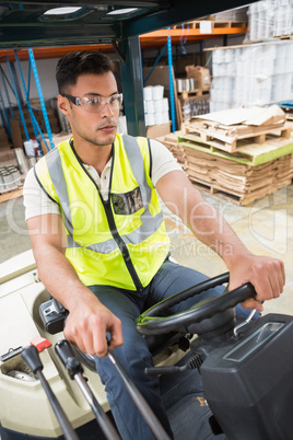 Driver operating forklift machine in warehouse