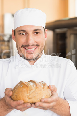 Baker showing freshly baked loaf