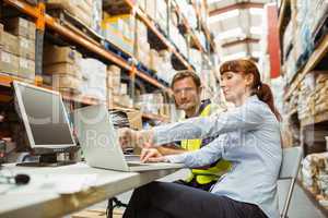 Warehouse worker and manager looking at laptop