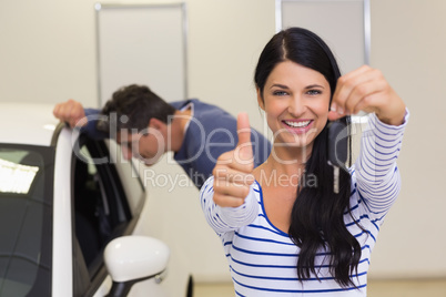 Customer holding her new car key while giving thumbs up