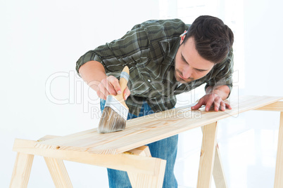 Worker using brush on wooden plank