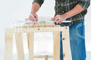 Worker using spirit level to mark on wooden plank