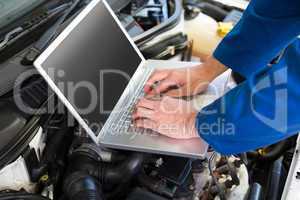 Mechanic using laptop on car