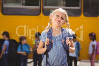 Cute pupils smiling at camera by the school bus
