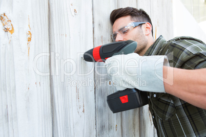 Carpenter drilling wooden cabin