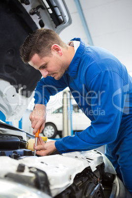 Mechanic using screwdriver on engine