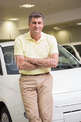 Smiling customer leaning on car with arms crossed