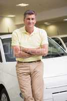 Smiling customer leaning on car with arms crossed