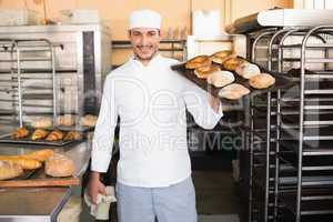 Baker holding tray of bread