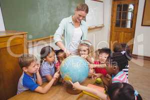 Cute pupils and teacher in classroom with globe