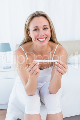 Smiling blonde woman holding pregnancy test