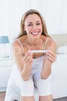 Smiling blonde woman holding pregnancy test