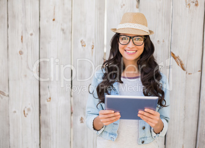 Pretty hipster smiling at camera holding tablet