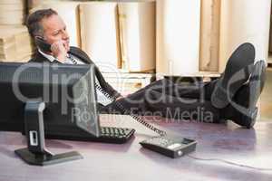 Warehouse manager using telephone at desk