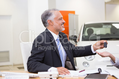 Smiling salesman giving a customer car keys