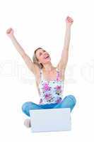 Happy blonde cheering with arms up near her laptop
