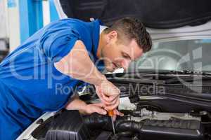 Mechanic using screwdriver on engine