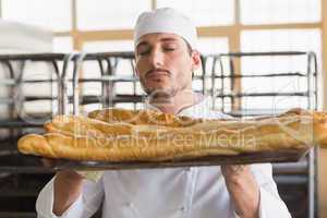 Baker smelling freshly baked baguettes