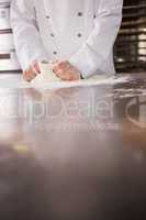 Close up of baker kneading dough on counter