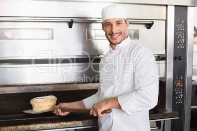 Happy baker taking out fresh loaf