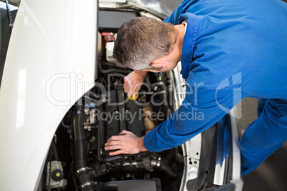 Mechanic examining under hood of car