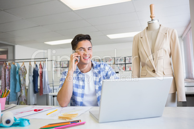 Smiling student on the phone while using laptop