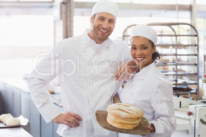 Team of bakers smiling at camera with loaf