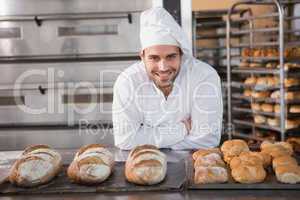 Happy baker standing near tray with bread