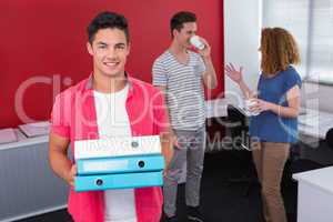Student holding pile of ring binder near classmates with coffee
