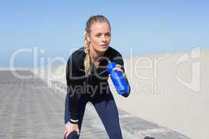 Fit blonde drinking water on the pier