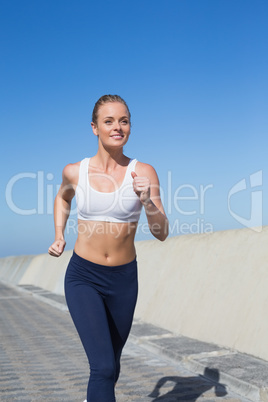 Fit blonde jogging on the pier