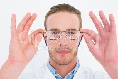 Optician in coat holding glasses