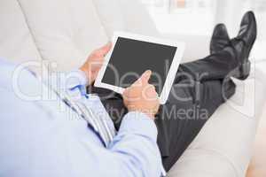 Relaxing businessman on a sofa with a tablet