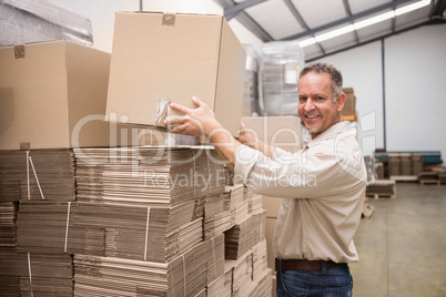 Smiling warehouse worker taking a box