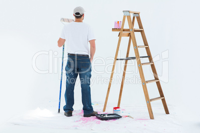 Man with paint roller standing by ladder