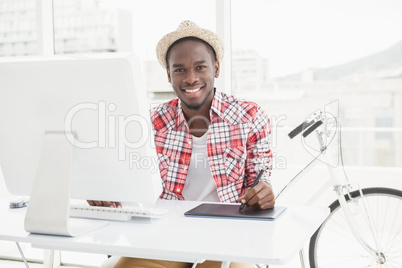 Smiling businessman in straw hat using digitizer