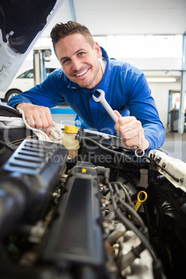 Mechanic smiling at the camera fixing engine