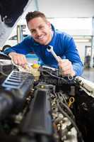 Mechanic smiling at the camera fixing engine