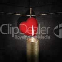 burning candle and red paper heart on a rope