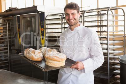 Happy baker showing tray with bread