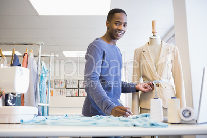 Smiling university student measuring waist of model