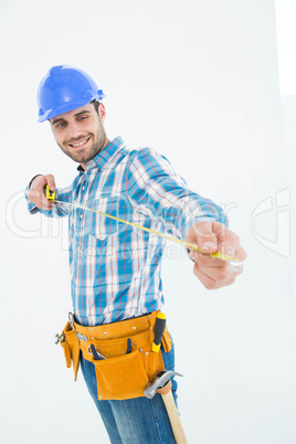 Happy repairman looking at measure tape