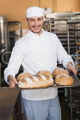 Baker holding tray of bread