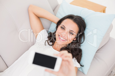 Pretty brunette taking a selfie on couch